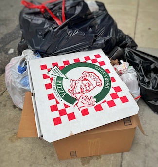 Pizza box in a pile of garbage and trash