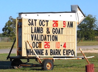 a portable outdoor sign highlighting lamb and goat validation at an expo