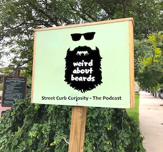sign in a park to highlight a podcast about facial hair, the trends and what we like.  Street Curb Curiosity - The Podcast