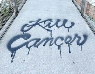 the words kill cancer, spray paint on a city sidewalk