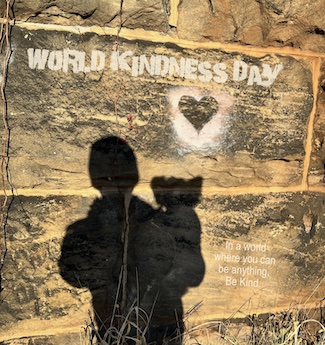 a shadow of a man and a small dog on a wall with a heart on it, for world kindness day in november