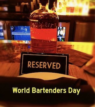 a reserved sign on a bar next to a bottle of bourbon for world bartenders day.