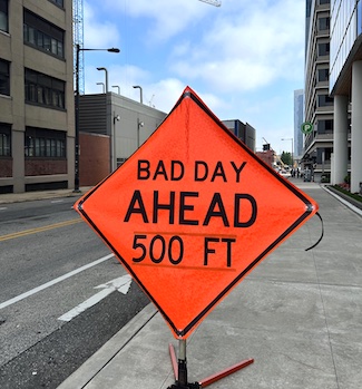 a bright orange road sign warning there is a bad day ahead.