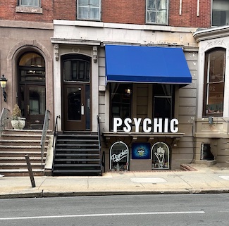 a psychic store with a large business sign on a city street