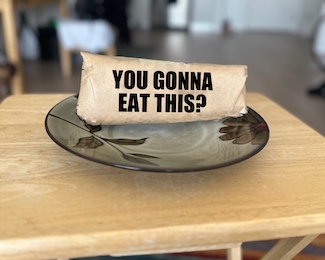 a sandwich or hoagie wrapped in brown paper on a plate at home