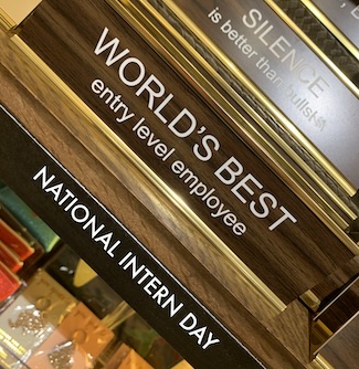 a desk sign that says "World's best entry level employee" for national Intern Day in July