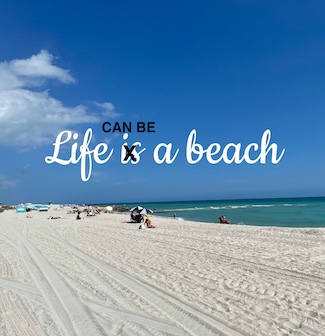 A white sand beach by the ocean, with a few people enjoying the view 