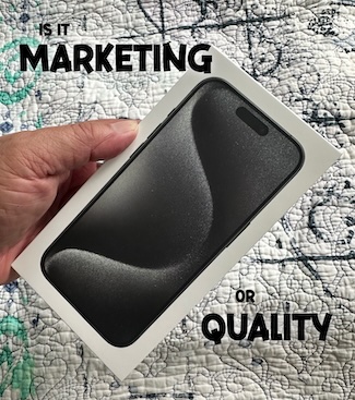 a hand holding the box of the new Apple iPhone 15, back titanium model.