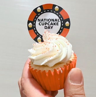 a hand holding a vanilla cupcake for national cupcake day in december