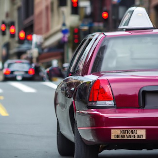 a red wine colored taxi cab with a bumper sticker to celebrate national drink wine day