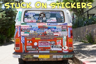an old van parked, covered with stickers of all kinds, parked at a curb on a sunny day