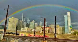 a colorful full rainbow over the city of philadelphia on a spring day
