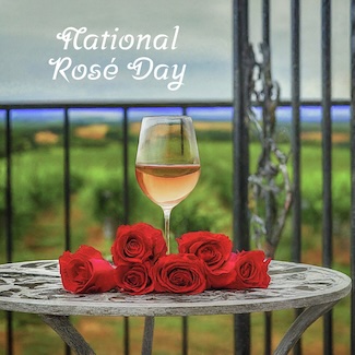 a glass of rose wine on an outdoor table with roses, for national rose day