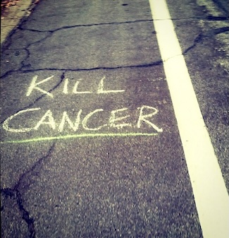 the words kill cancer hand written in chalk on a roadway