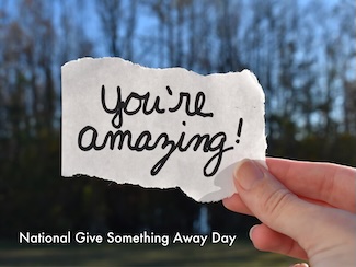 a hand outdoors holding a torn piece of paper that reads: "you're amazing"
