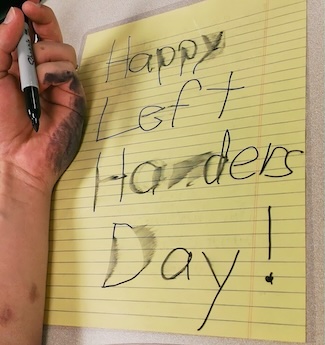 an ink smudged hand when writing a note for international left handers day