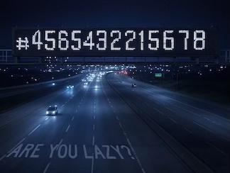 A dark multi lane highway, with a large lit sign overhead, showing a digital version of a very large number