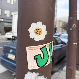 a white flower sticker that says "you look good" on a city street pole