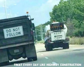 two construction trucks on a highway, with funny conflicting signs