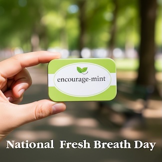 a hand holding a small box of encourage mints, in a forest area