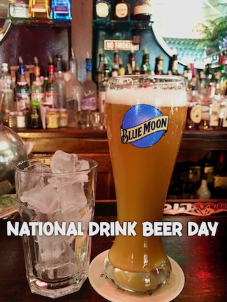 a glass off ice and a tall cold blue boom beer on a bar for national drink beer day in September