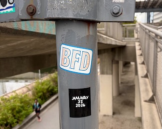 a BFD sticker on a pole in a city side walk walk way