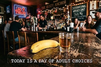 a banana and a shot of whiskey sitting on a bar for a choice on international whiskey day
