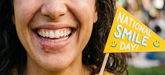a big bright smile on a woman's face that also has cold sores, for national smile day on the last day of May