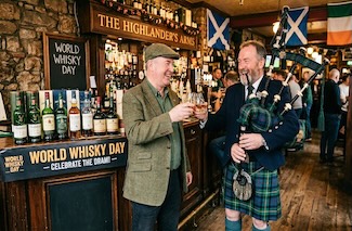 two older men from Ireland and Scotland in an Irish bar, with bagpipes, celebrating world whisky day in May. Or is it whiskey?