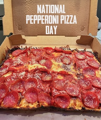 a Detroit style pepperoni pizza in its box just opened to show off the tasty tears on this special national day of celebration of pizza