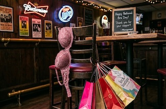 a fun but fake take on a local dive bar, with a pink bra and shopping bags hanging from one of the bar's chairs.